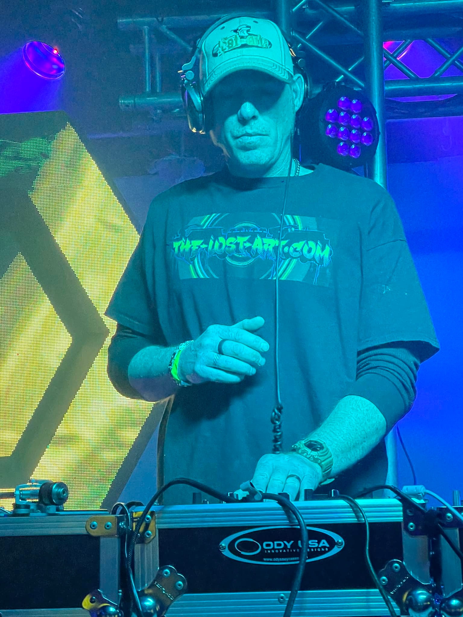 DJ Natural Nate® at the Odyssey case decks in The-Lost-Art.com shirt under yellow LED lighting